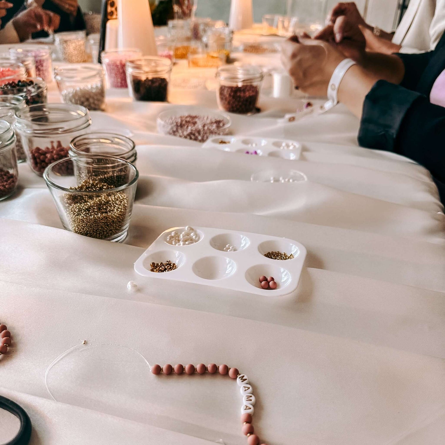 Personen fertigen Armbänder an Tisch – Perlenschmuck Workshop Berlin, DIY Schmuck, Perlen kreativ.