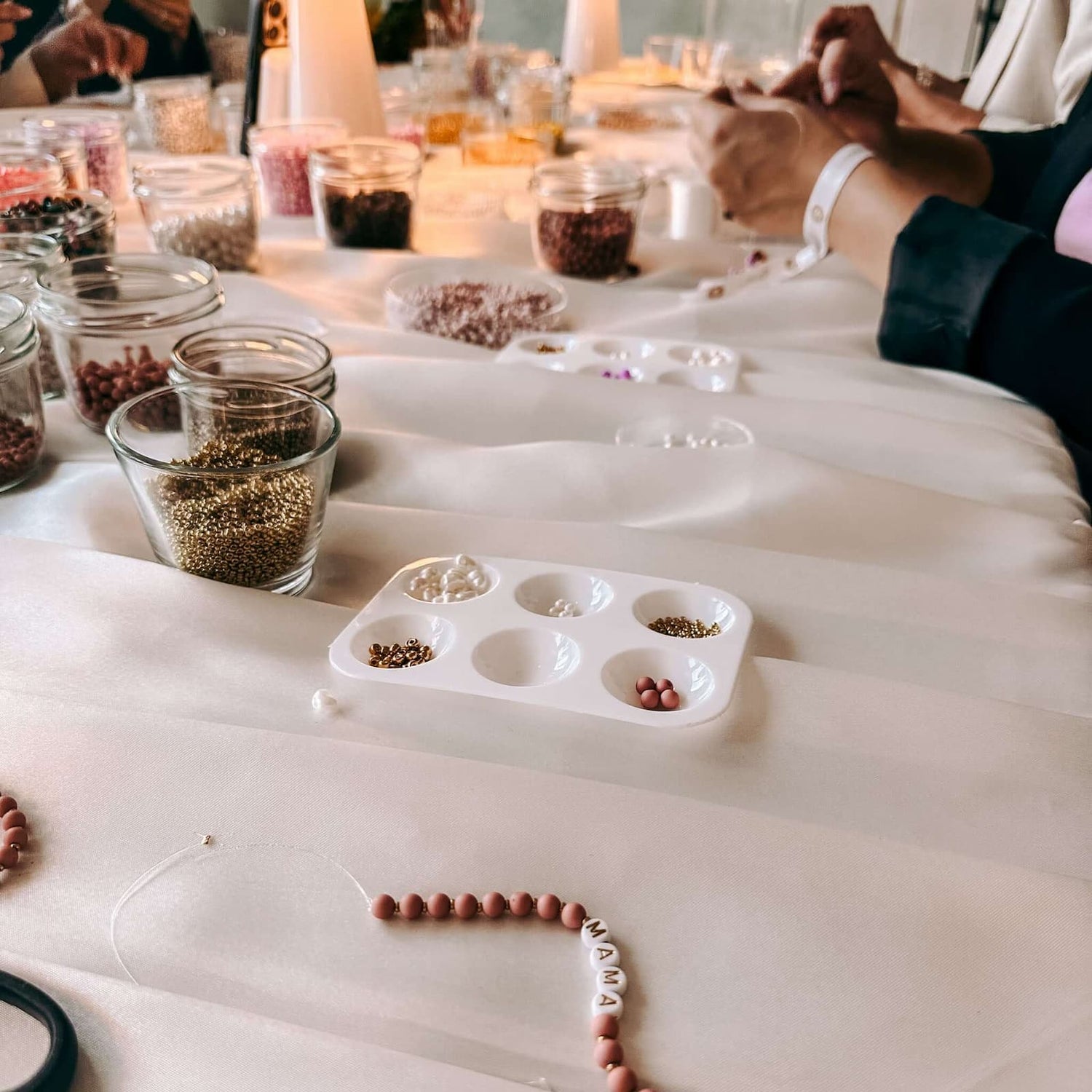 Personen fertigen Armbänder an Tisch – Perlenschmuck Workshop Berlin, DIY Schmuck, Perlen kreativ.