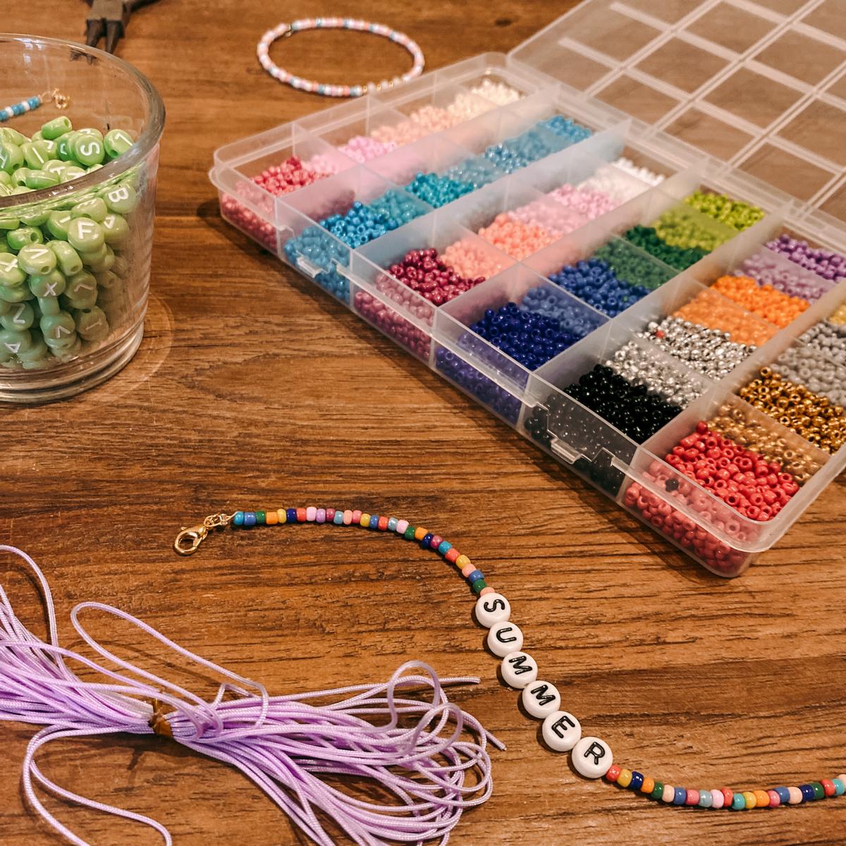 Box mit bunten Perlen und Armband „Summer“ auf Tisch – DIY Perlenschmuck Workshop, Armband selber machen.