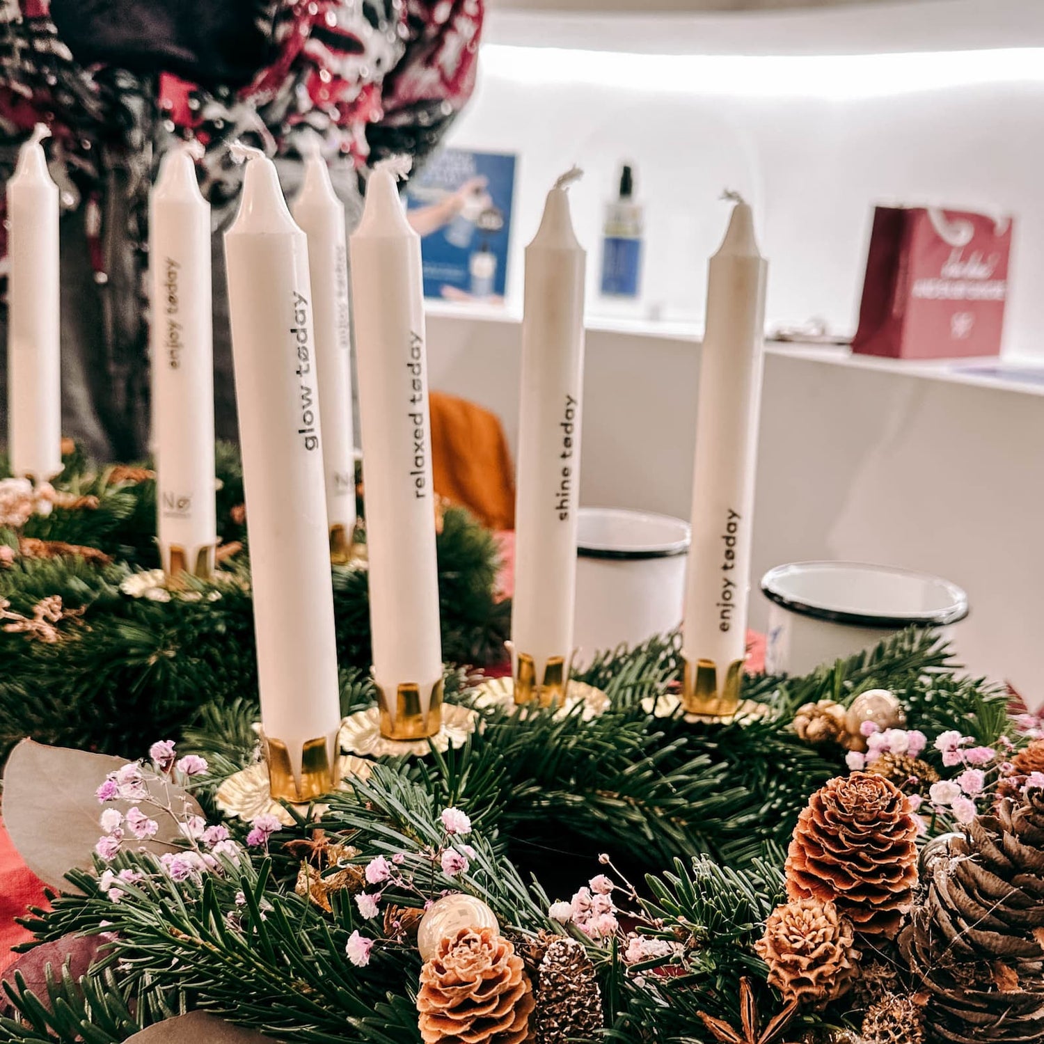 Vier Kerzen mit unterschiedlichen Schriftzügen auf weißem Adventskranz beim Kerzen Tattoo Workshop von GRIMMS GARTEN, kreatives Teamevent in Berlin