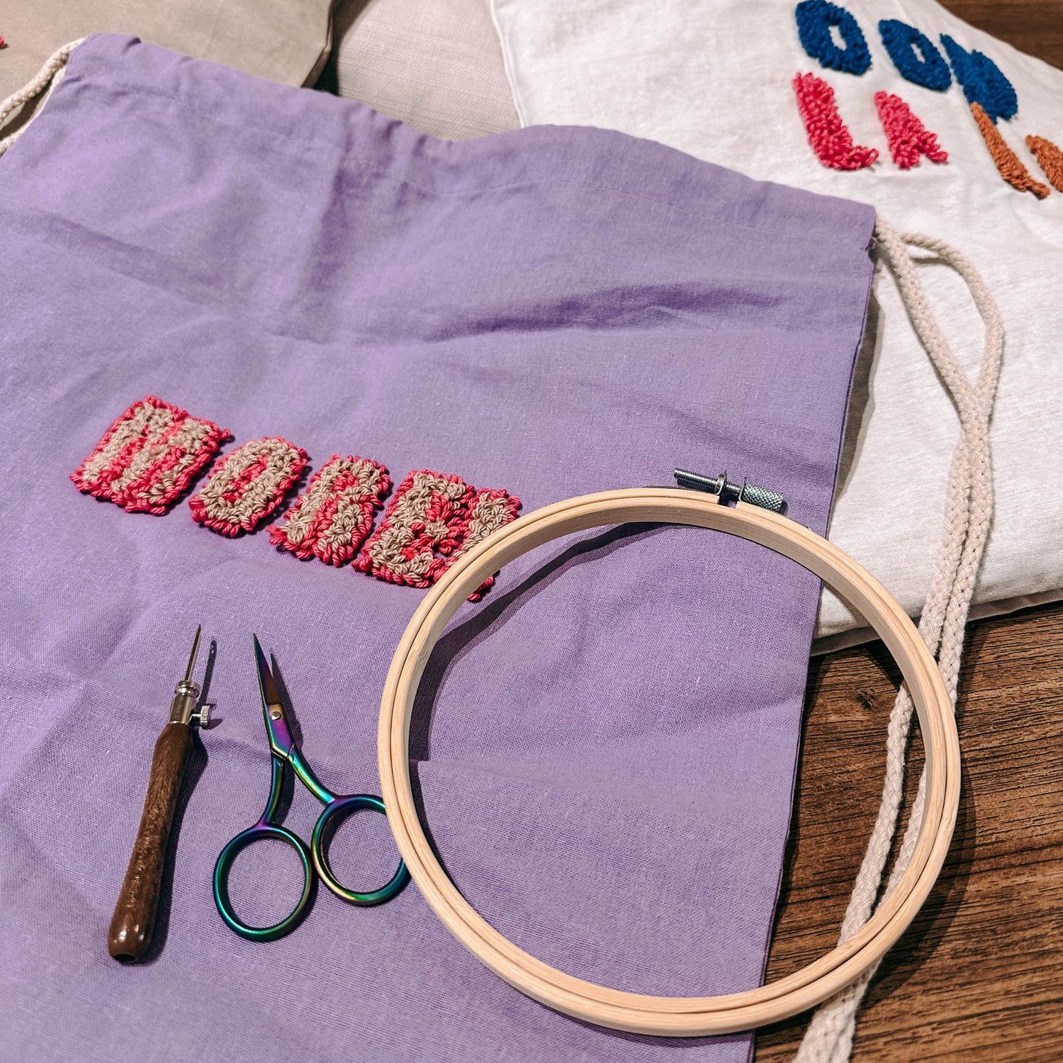 Lilaner Jutebeutel „MORE“ auf Tisch mit Materialien – DIY Punch-Needle Workshop Berlin.