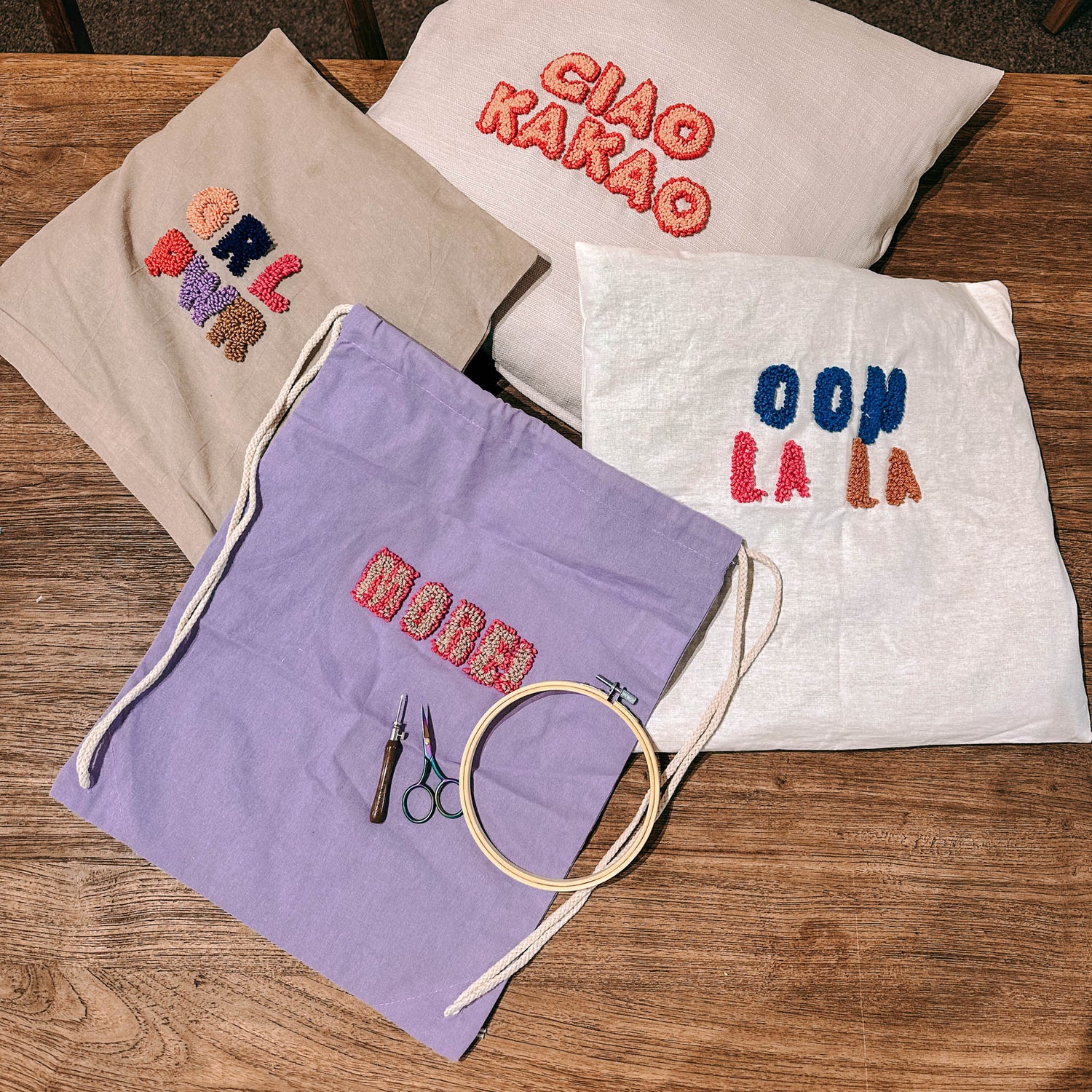 Verschiedene Stoffe mit Sprüchen, Materialien und Wolle auf Tisch – Punch-Needle Workshop Berlin.