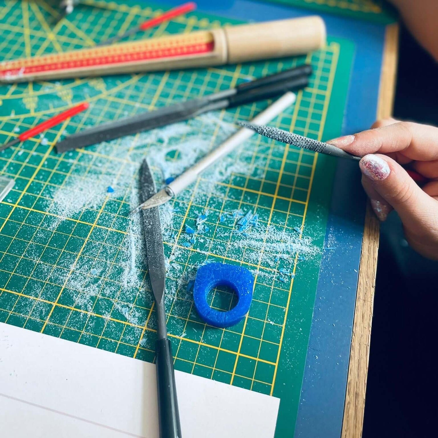 Verschiedene Materialien auf Matte mit Pfeilen – DIY Ring Workshop, Lost-Wax-Technik, Schmuckgestaltung.
