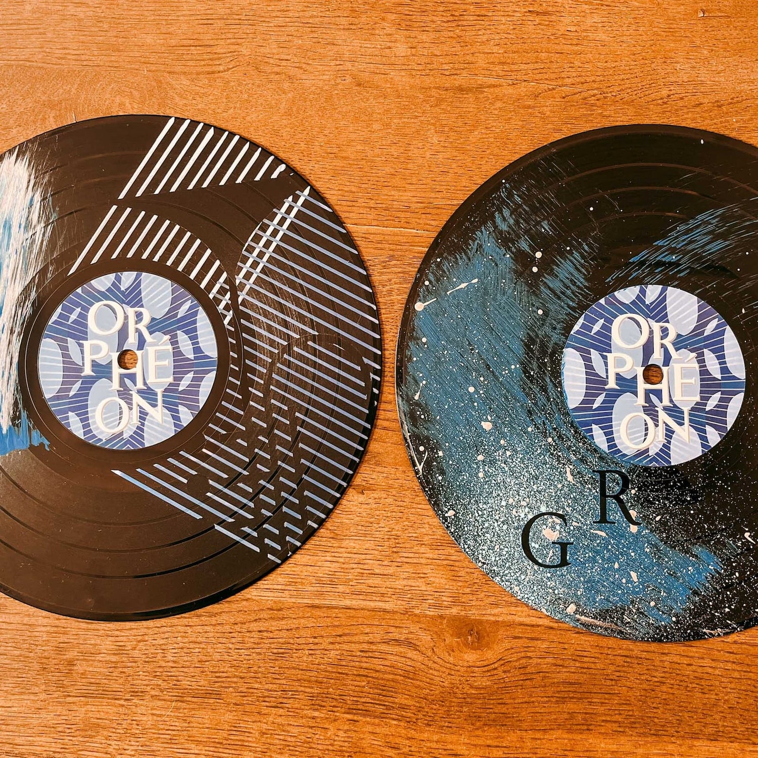 Zwei bemalte Schallplatten mit unterschiedlichen Farbstrichen und Mustern auf dem Tisch beim Vinylplatten bemalen Workshop von GRIMMS GARTEN, Kreativkurs in Berlin