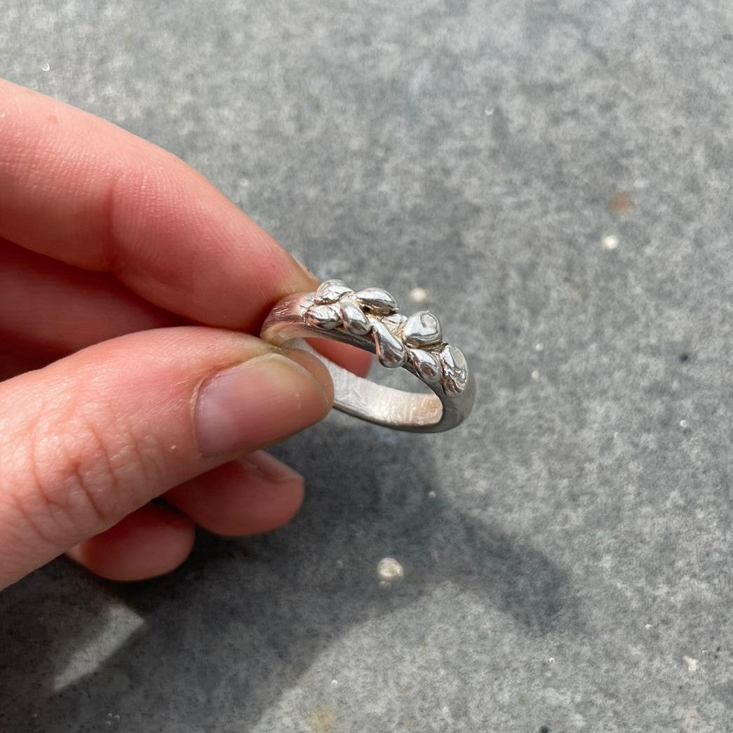 Silberner Ring von zwei Fingern gehalten – DIY Schmuck Workshop, Ring selbst designen, Handarbeit.