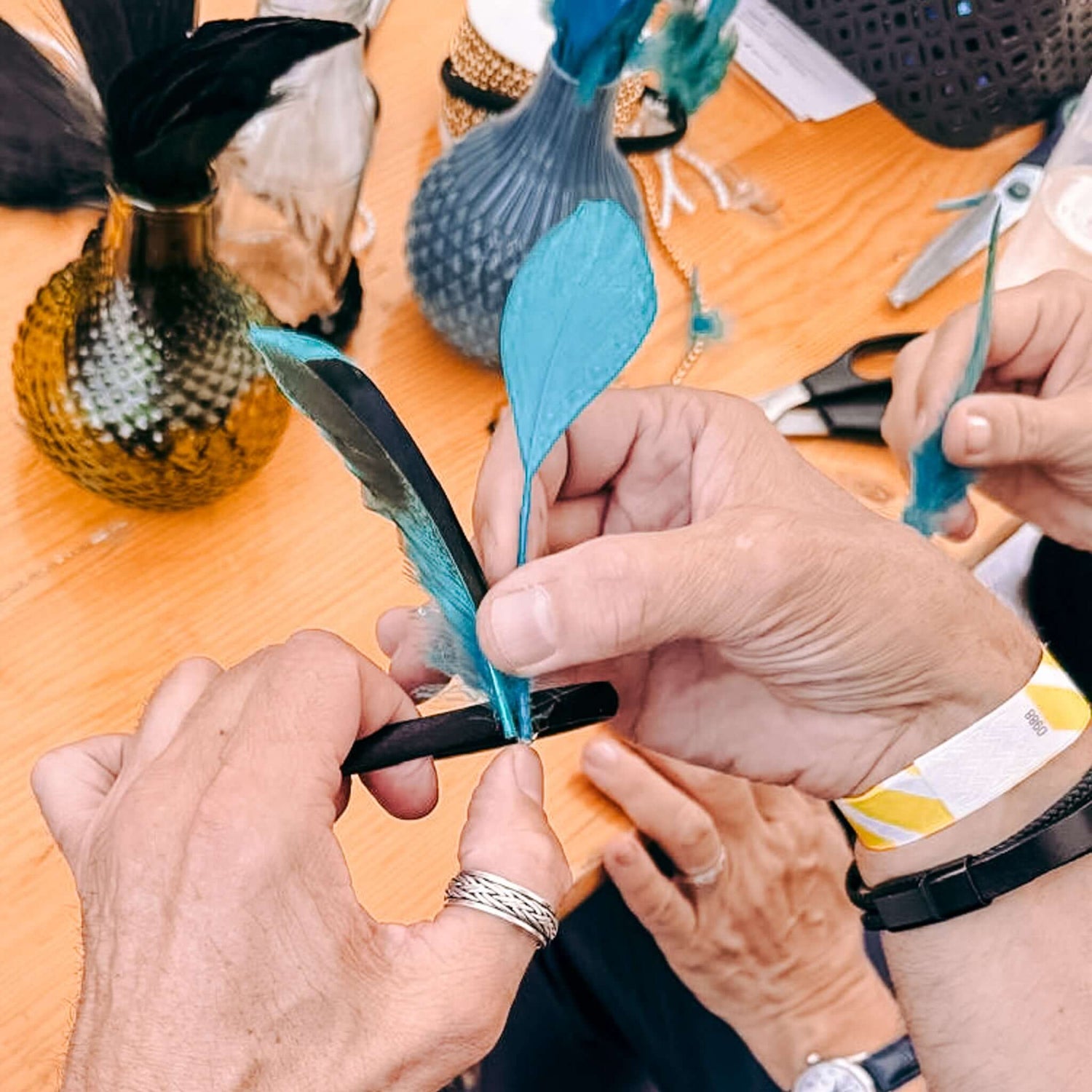 Zwei Hände kleben Feder an Haarreif – 20er Jahre Haarschmuck Workshop, Teamevent oder JGA kreativ gestalten.