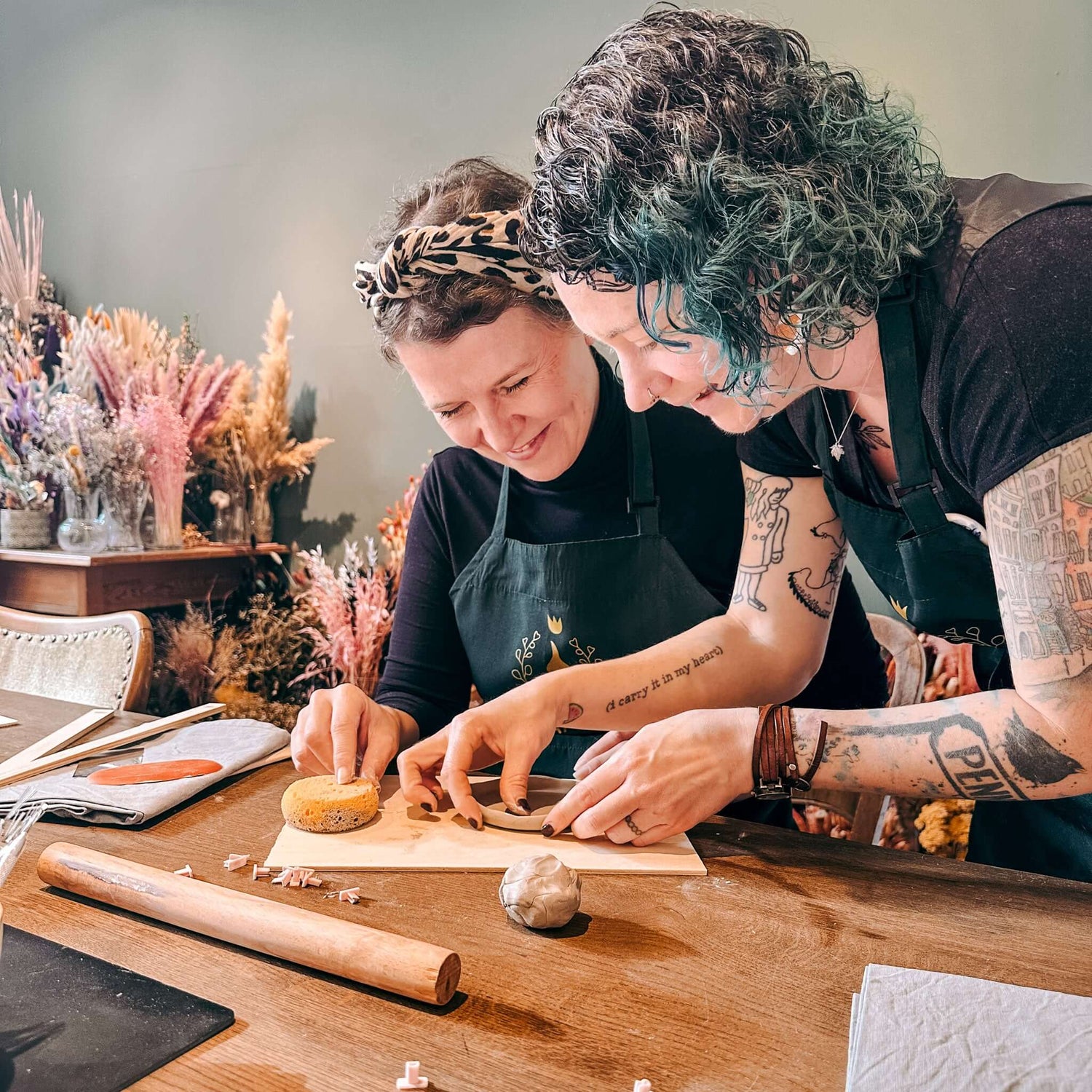 Kursleiterin zeigt Teilnehmerin richtige Tonform-Technik – persönliche Anleitung im Töpferkurs Englisc