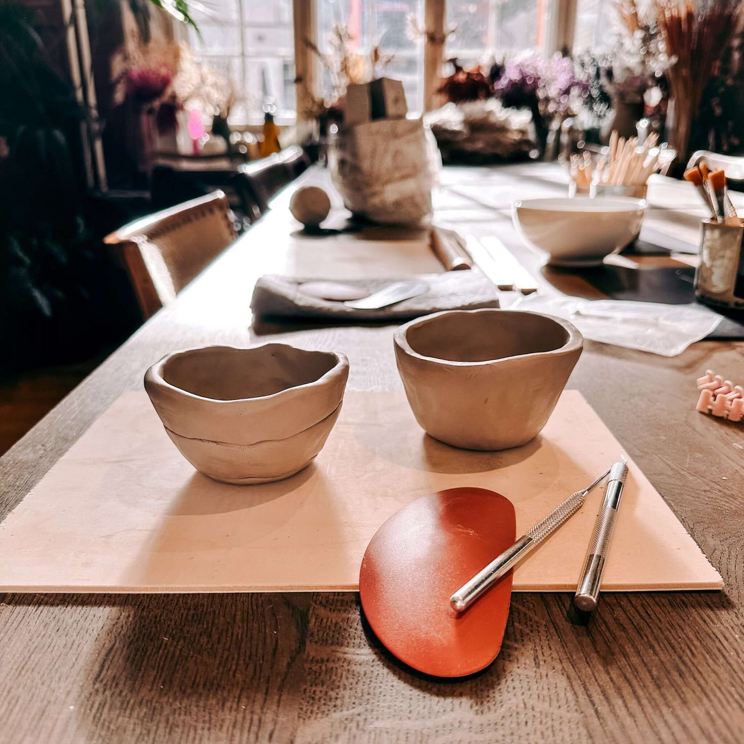 Zwei handgeformte Tontassen mit Töpferwerkzeugen auf rustikaler Holzplatte – Handbuilding Pottery Workshop Grimms Garten