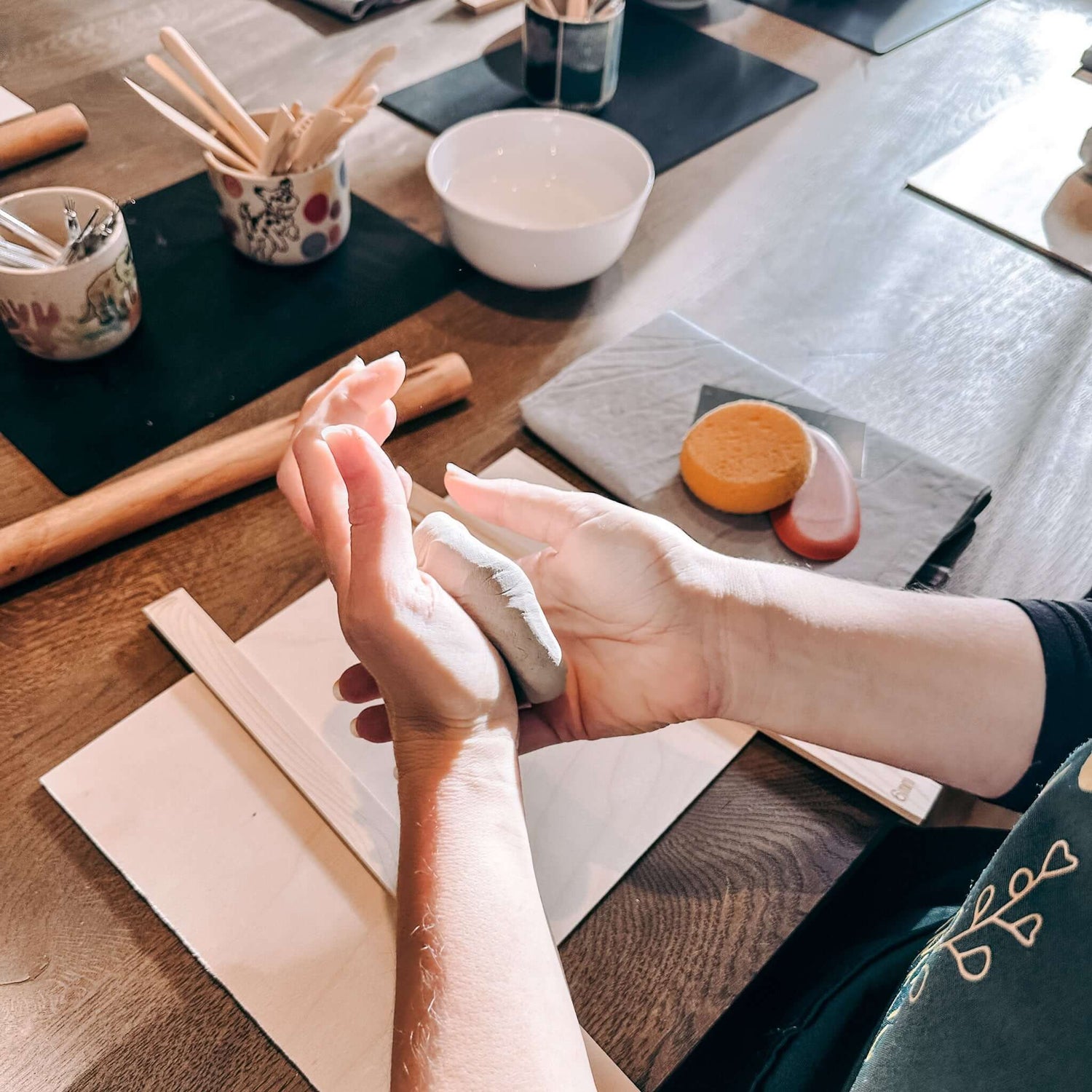 Zwei Hände kneten Ton zu flacher, runder Platte – Grundtechnik Handformen Ton im Keramik Workshop