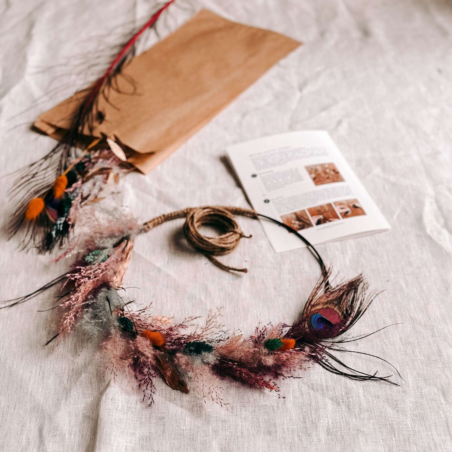 Farbiger Trockenblumenring Pfauenauge auf Tuch mit Blumen und Garn – kreative DIY Deko.