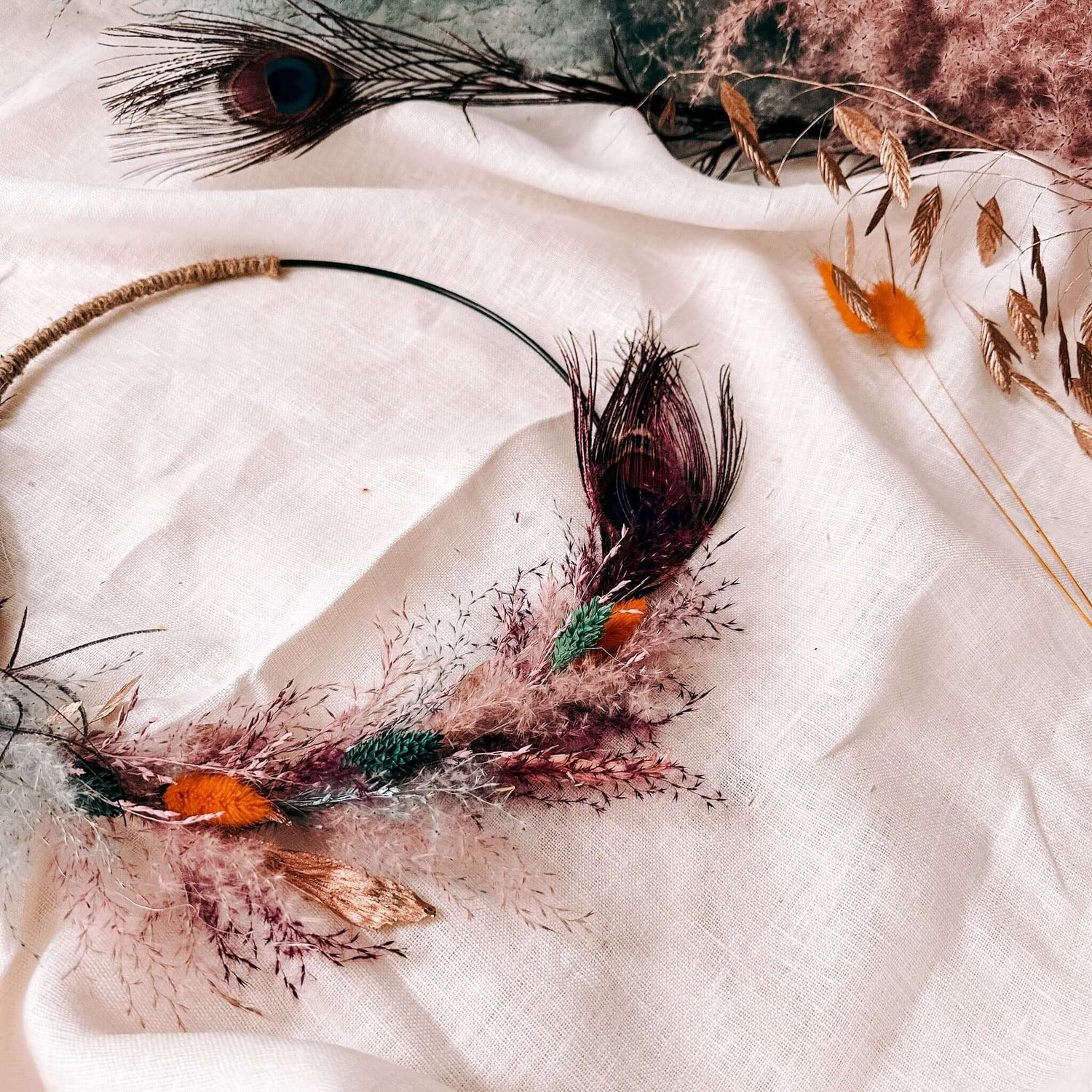 Nahaufnahme vom Trockenblumenring Pfauenauge mit bunten Blumen und Federn.