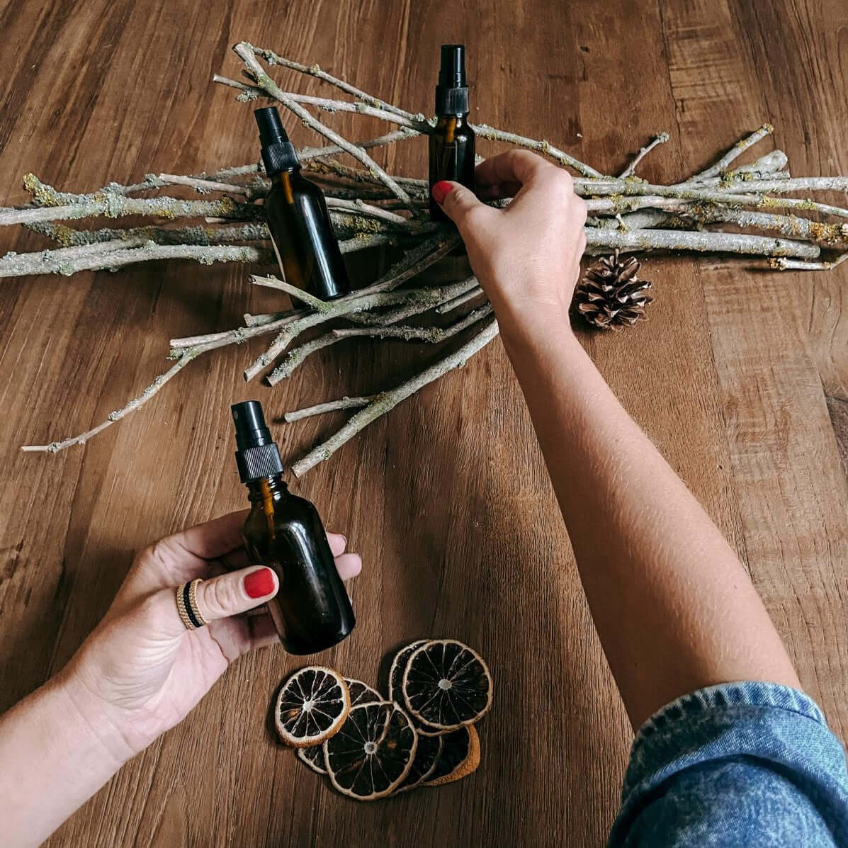 Hand hält zwei fertige Parfums, getrocknete Orangenscheiben im Hintergrund – naturkosmetik, parfum workshop berlin, diy duft, auch für Firmenevents.
