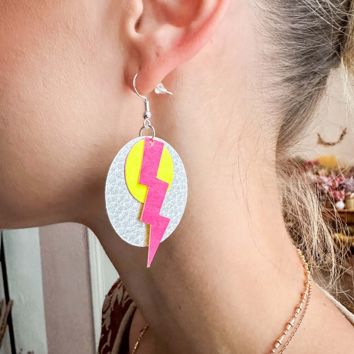 Nahaufnahme eines Ohres mit pink-gelbem Blitz-Ohrring aus veganem Leder – nachhaltiger Schmuck Workshop.