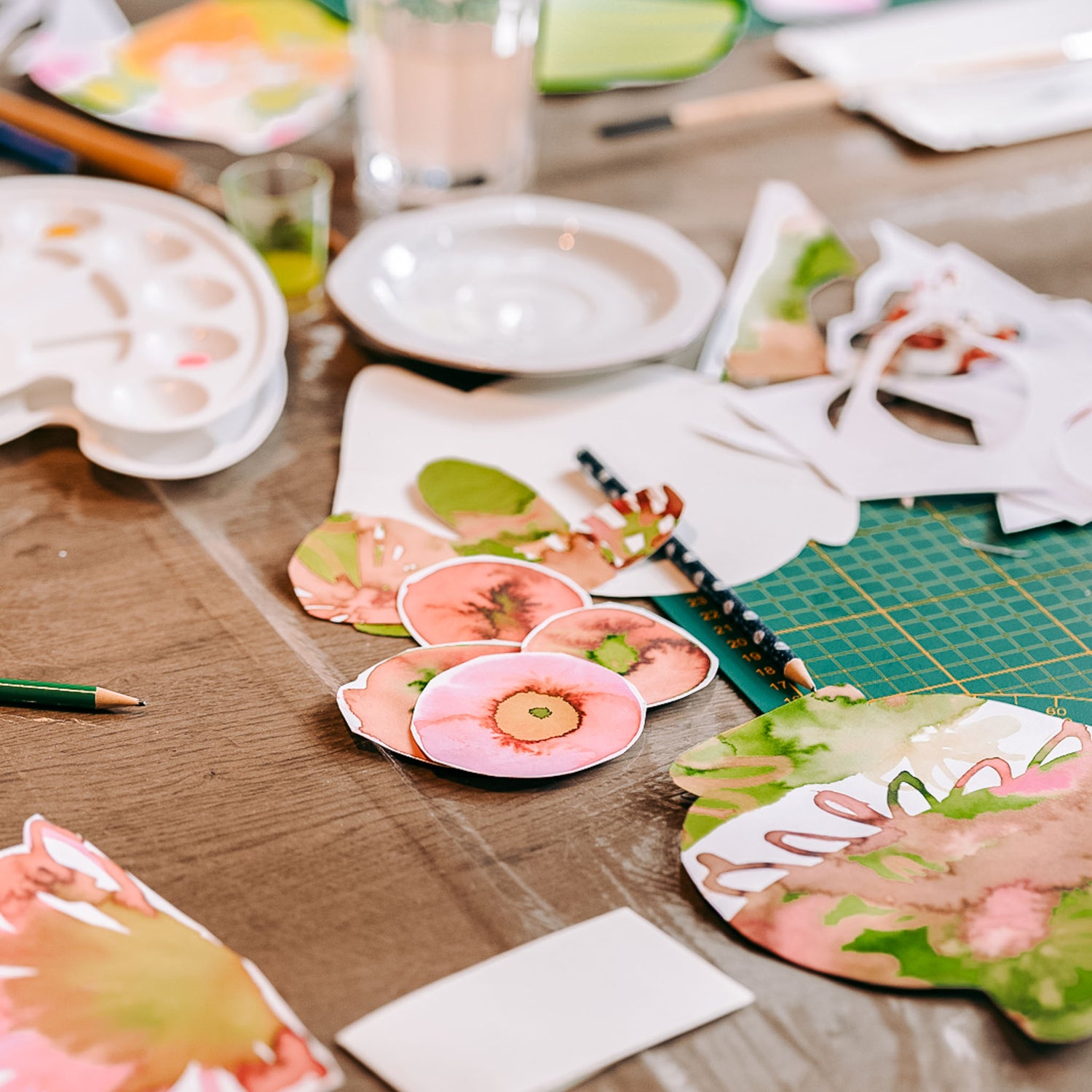 Rosa-grüne Blumenteile und Vasen auf Tisch mit Materialien – Aquarell Flower Bouquet DIY Workshop.