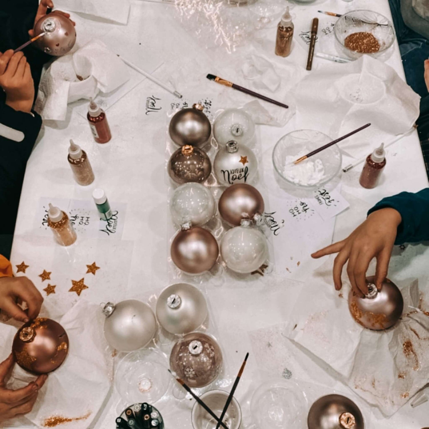 Mehrere Teilnehmer bemalen ihre Kugeln auf Tisch – Teamevent Weihnachtsworkshop kreativ.