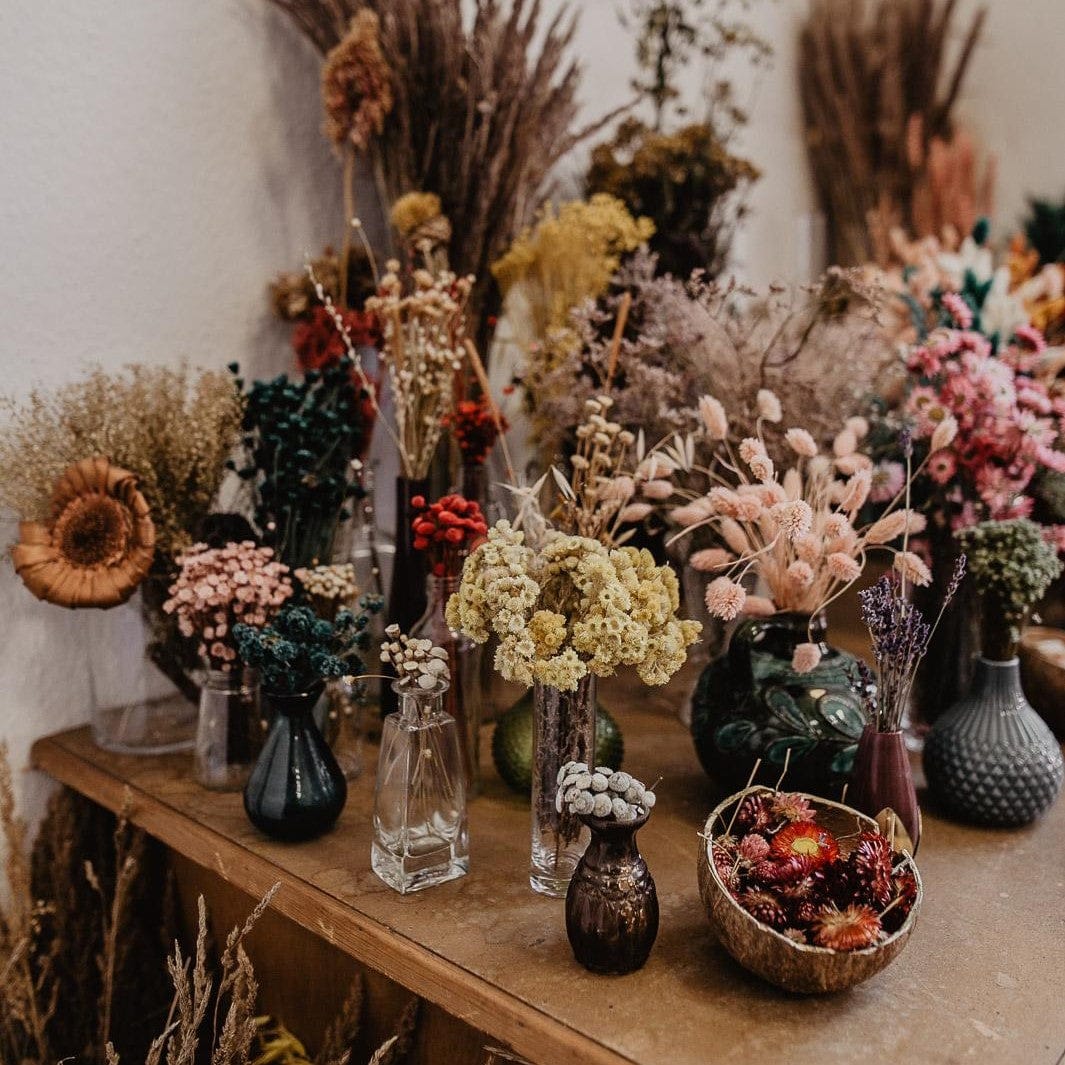 Tisch mit Vasen und verschiedenen Blumen – Fotokurs für Anfänger, kreative Bildkompositionen üben.