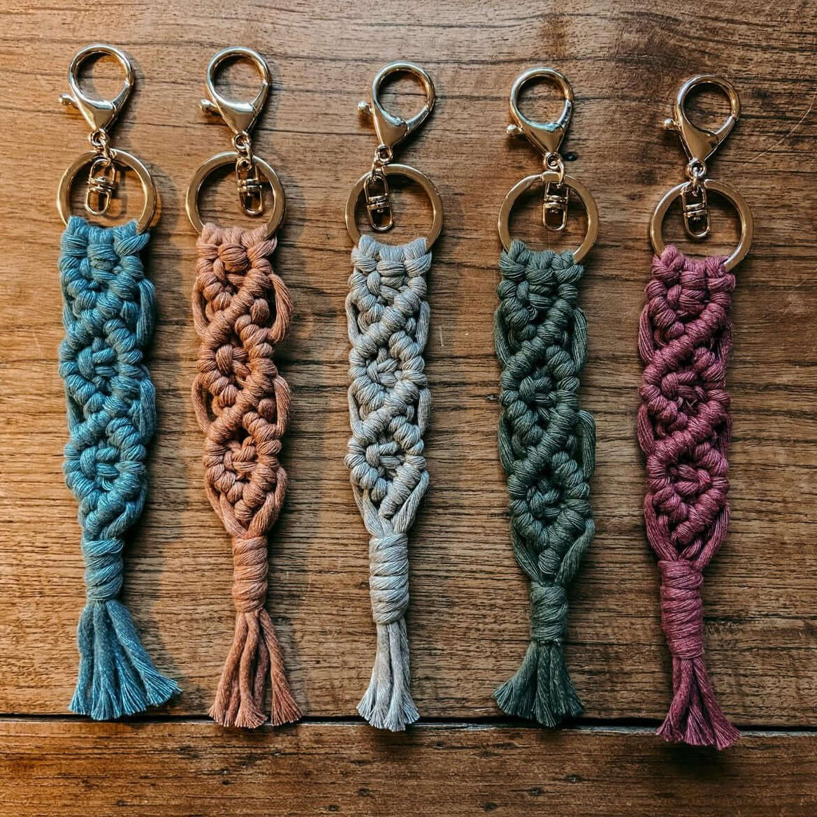 Verschiedene Makramee Schlüsselanhänger in bunten Farben auf Tisch arrangiert, Boho-Accessoire.