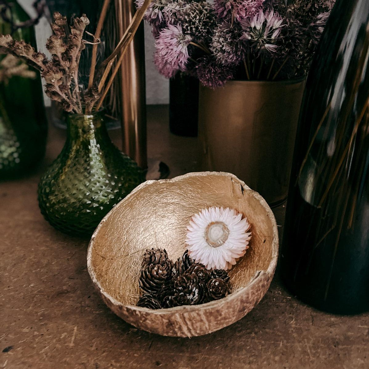 Schale mit Blume und kleinen Tannenzapfen, Vasen im Hintergrund – Fotoworkshop Grundlagen Belichtungszeit, ISO.
