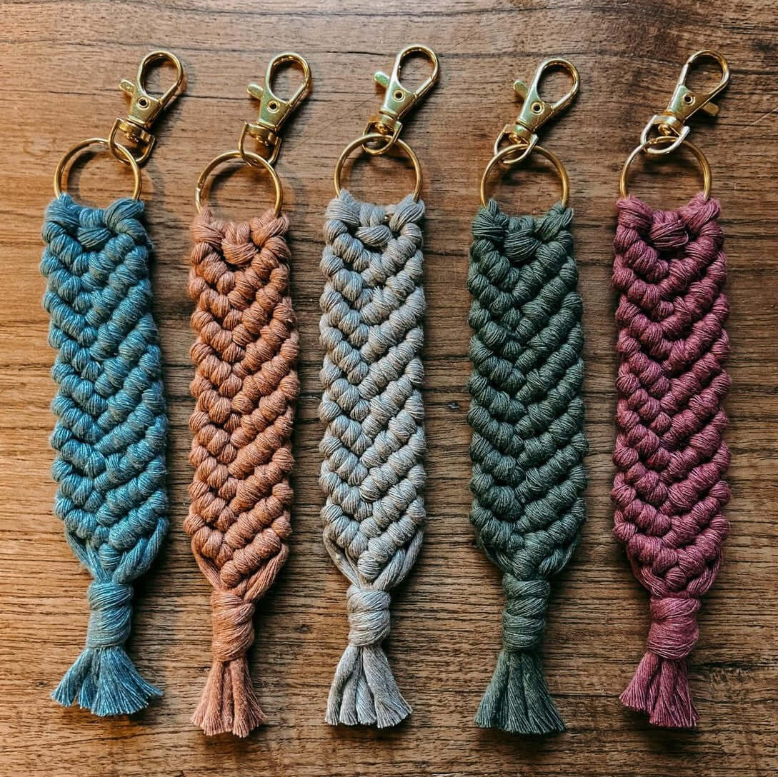 Verschiedene Makramee Schlüsselanhänger in bunten Farben auf Tisch arrangiert, Boho-Accessoire.