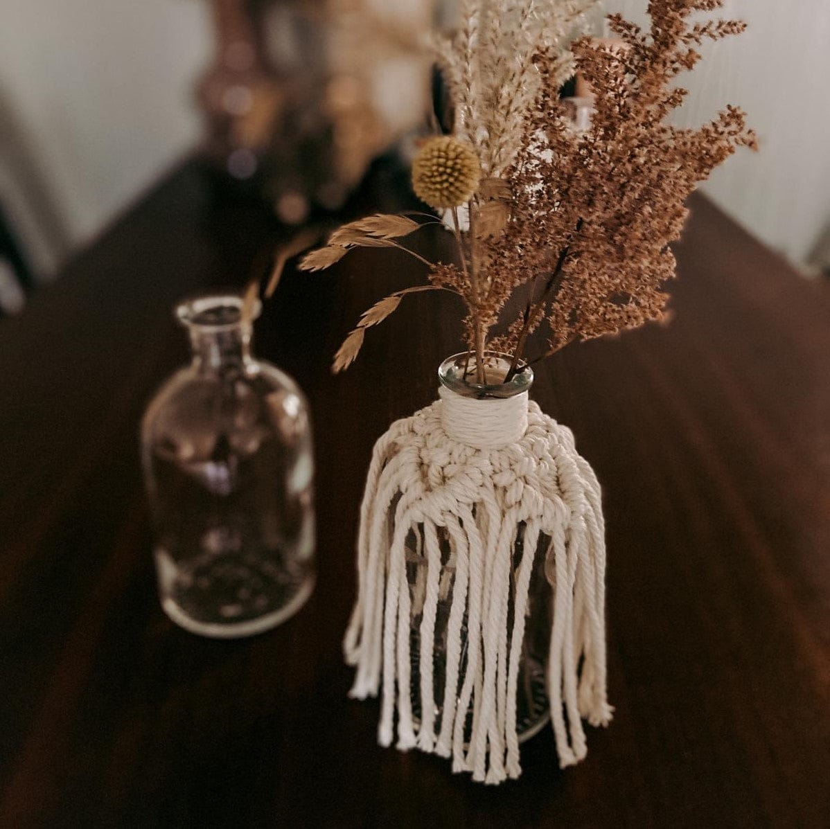 Fertige Makramee Mini Vase mit Blumen auf Tisch, handgemachtes Boho-Accessoire.