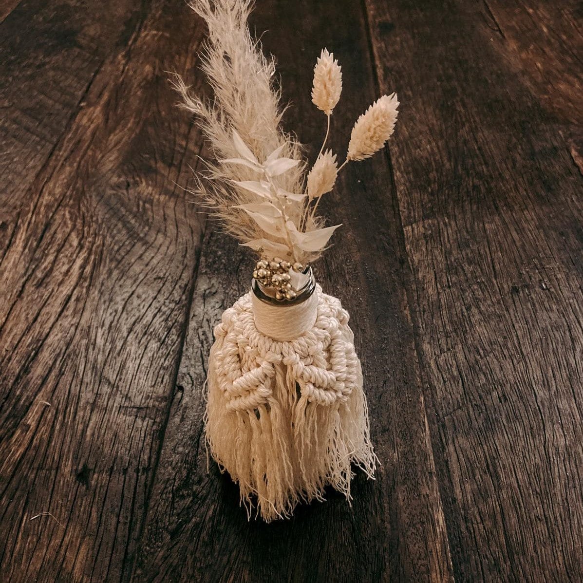 Makramee Vase auf Tisch mit vielen weißen Trockenblumen, stilvolle Dekoration.