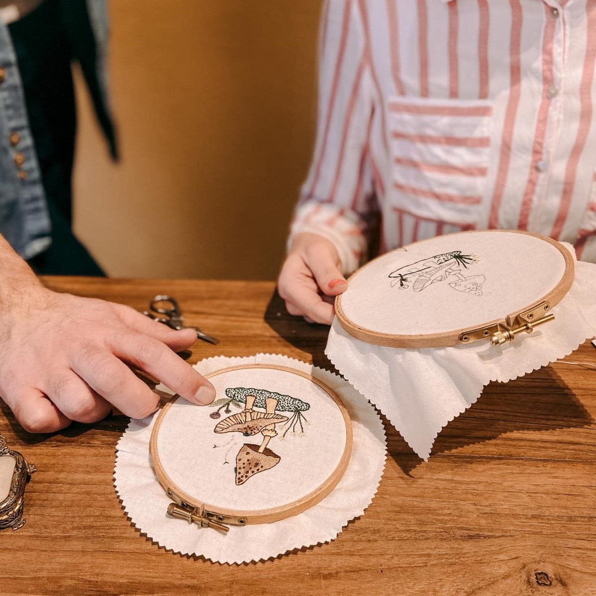 Fertiges Stickprojekt neben halbfertig gesticktem Pilz auf Tisch – Stickkunst.