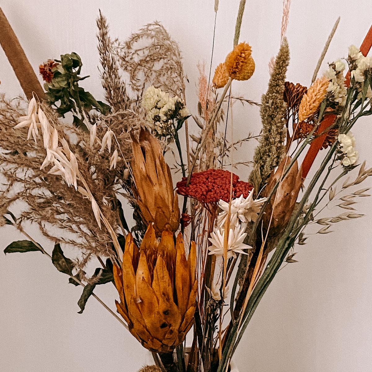 Nahaufnahme Trockenblumenstrauß Sonnenschein, rote und orange Blüten, stilvolle Deko für Tisch oder Raum.