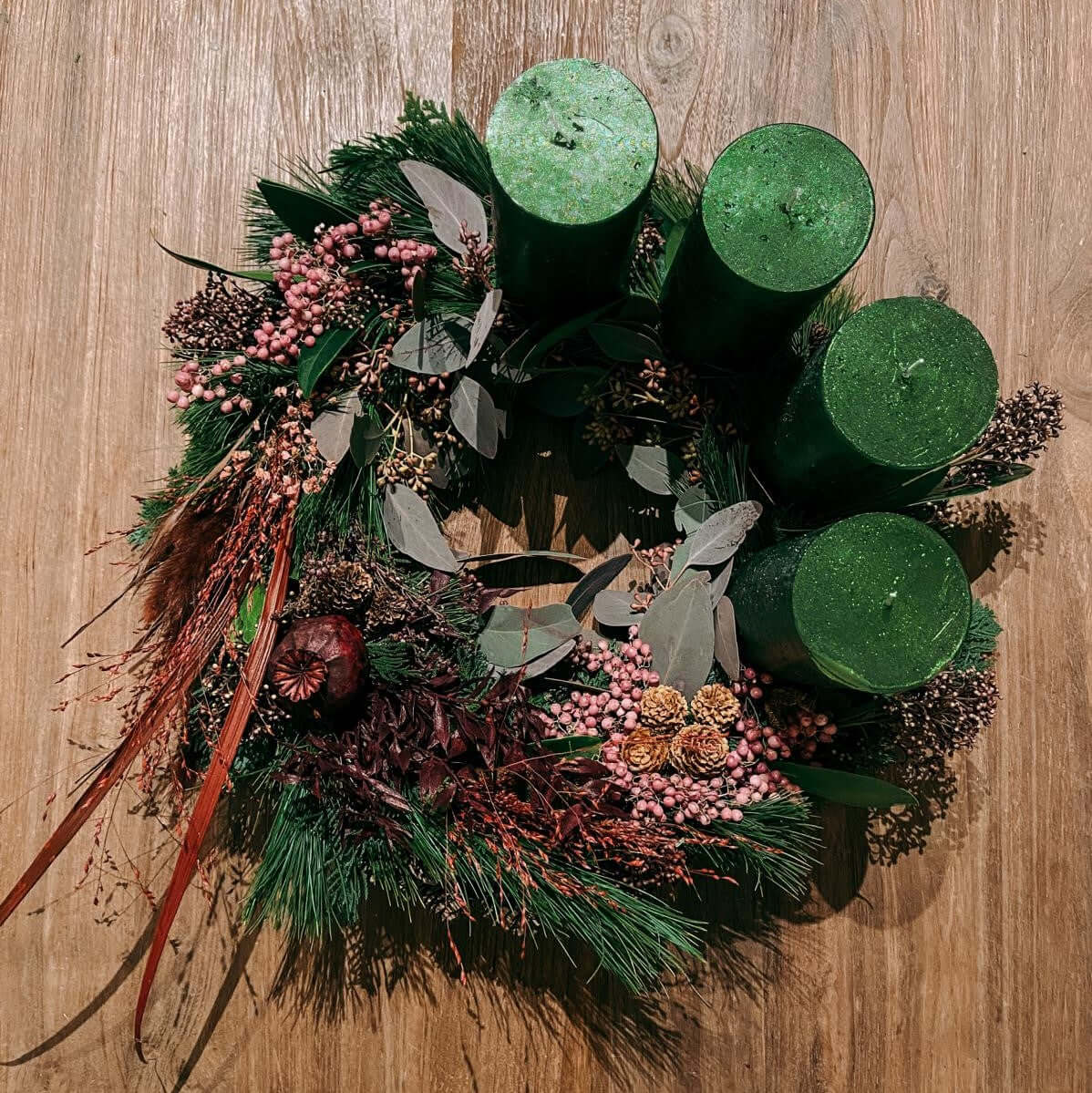 Nahaufnahme eines festlich geschmückten adventskranz mit roten Kerzen und Tannenzweigen.Auch als Firmenevent buchbar.