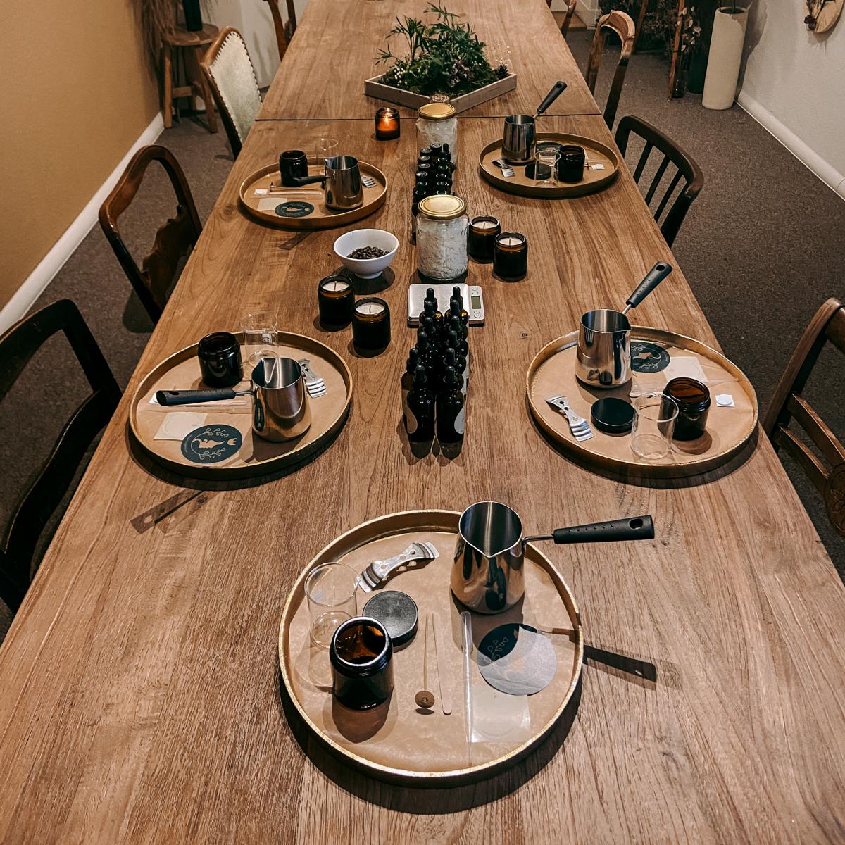 Tisch mit goldenen Tabletts und Arbeitsstationen für vegane Duftkerzen, Materialien bereit für Firmenevent.