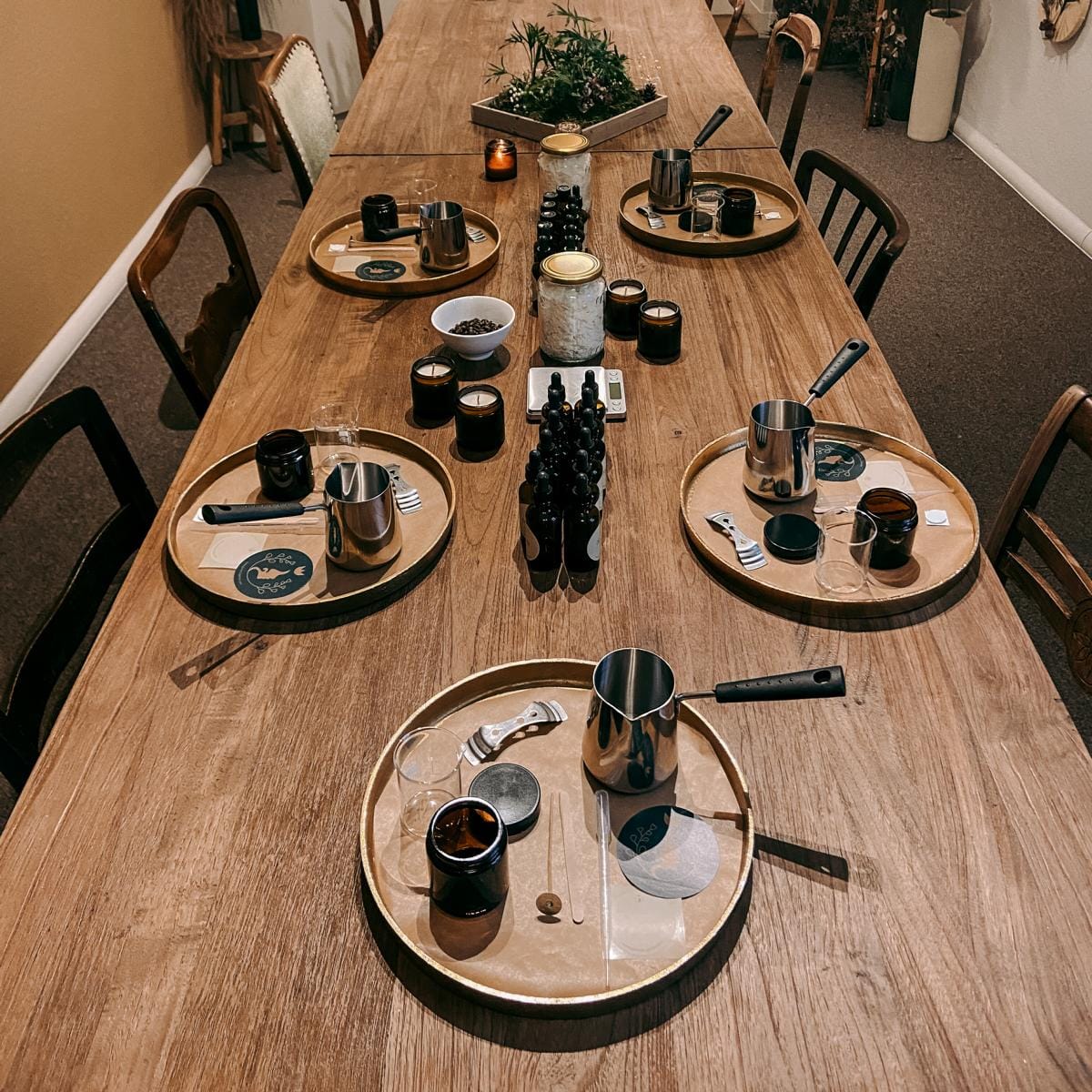 Tisch mit goldenen Tabletts und Arbeitsstationen für vegane Duftkerzen, Materialien bereit für Firmenevent.