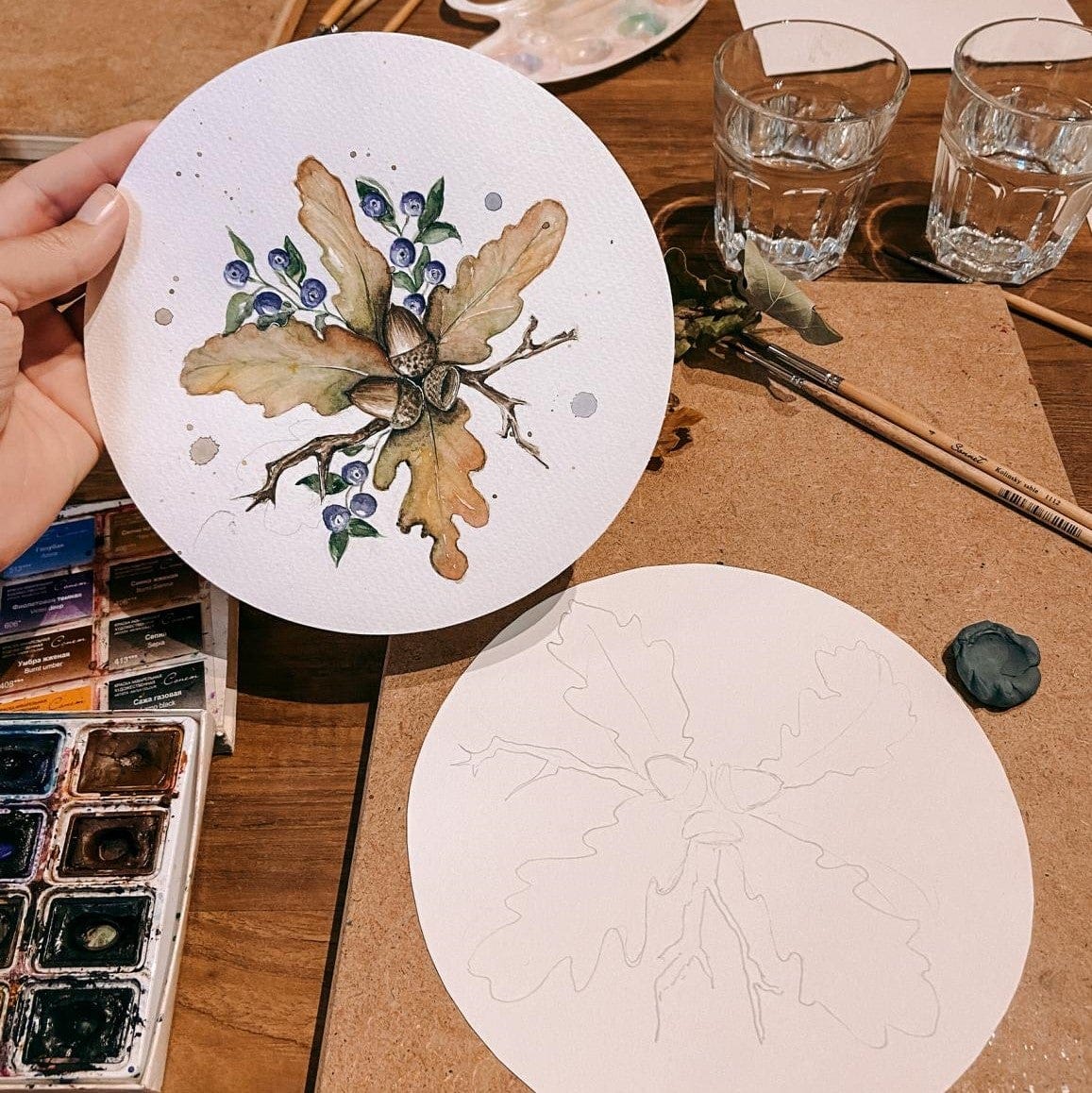 Fertiges Aquarellbild mit angefangener Skizze, Farben und Pinsel auf Tisch – Herbstmotiv.