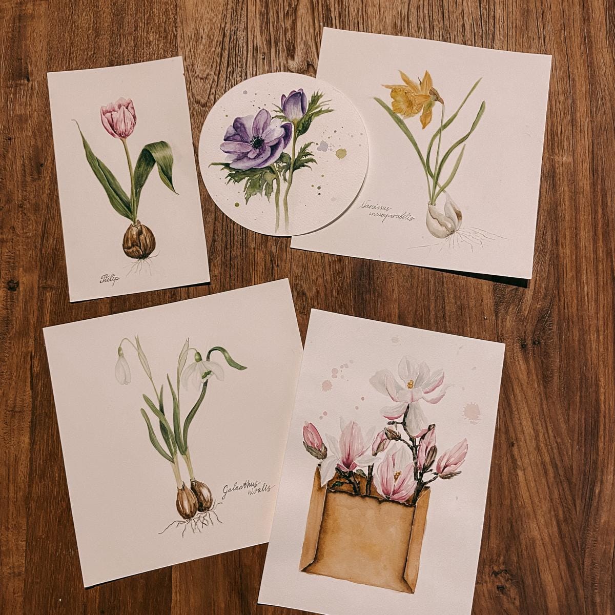 Fünf fertige Aquarellbilder mit Blumen auf Holztisch – Kreativer Magnolien-Workshop.