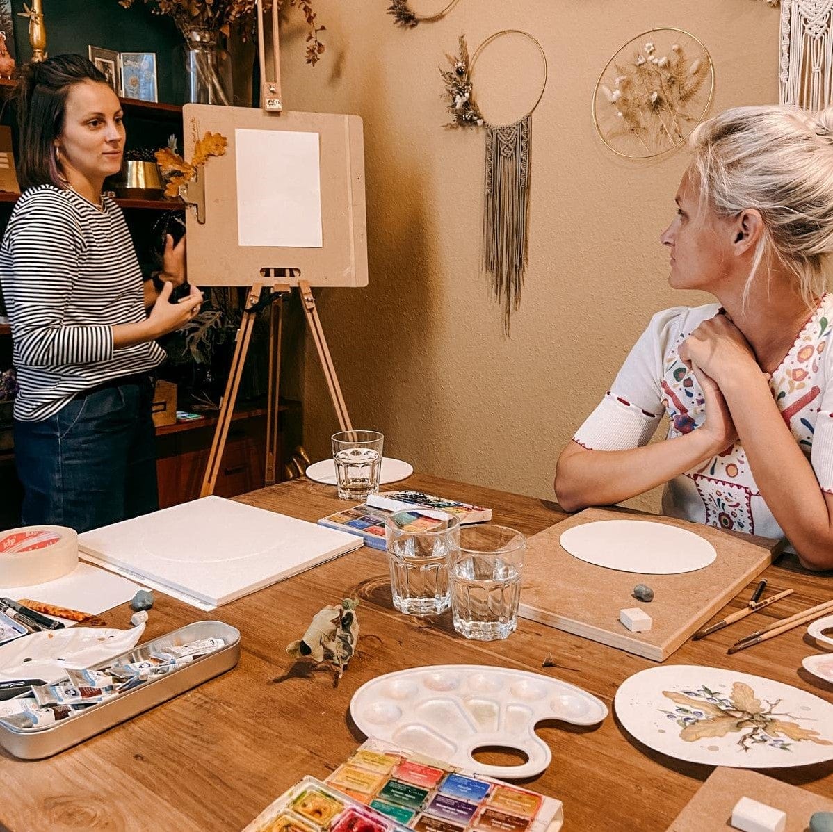 Frau erklärt Aquarelltechniken an Teilnehmerin – Herbstfarben, Mischungen und Tipps.