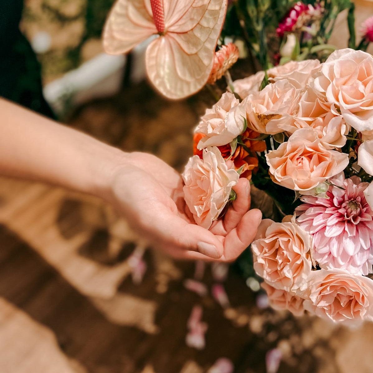 Hand hält Rosen – Floristik Workshop zum Blumenkranz binden für Junggesellinnenabschied.