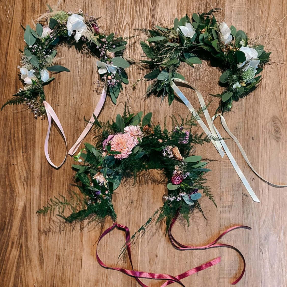 Drei fertige Blumenkränze auf Holztisch – Flower Crown Workshop Berlin, auch als Firmenevent buchbar.