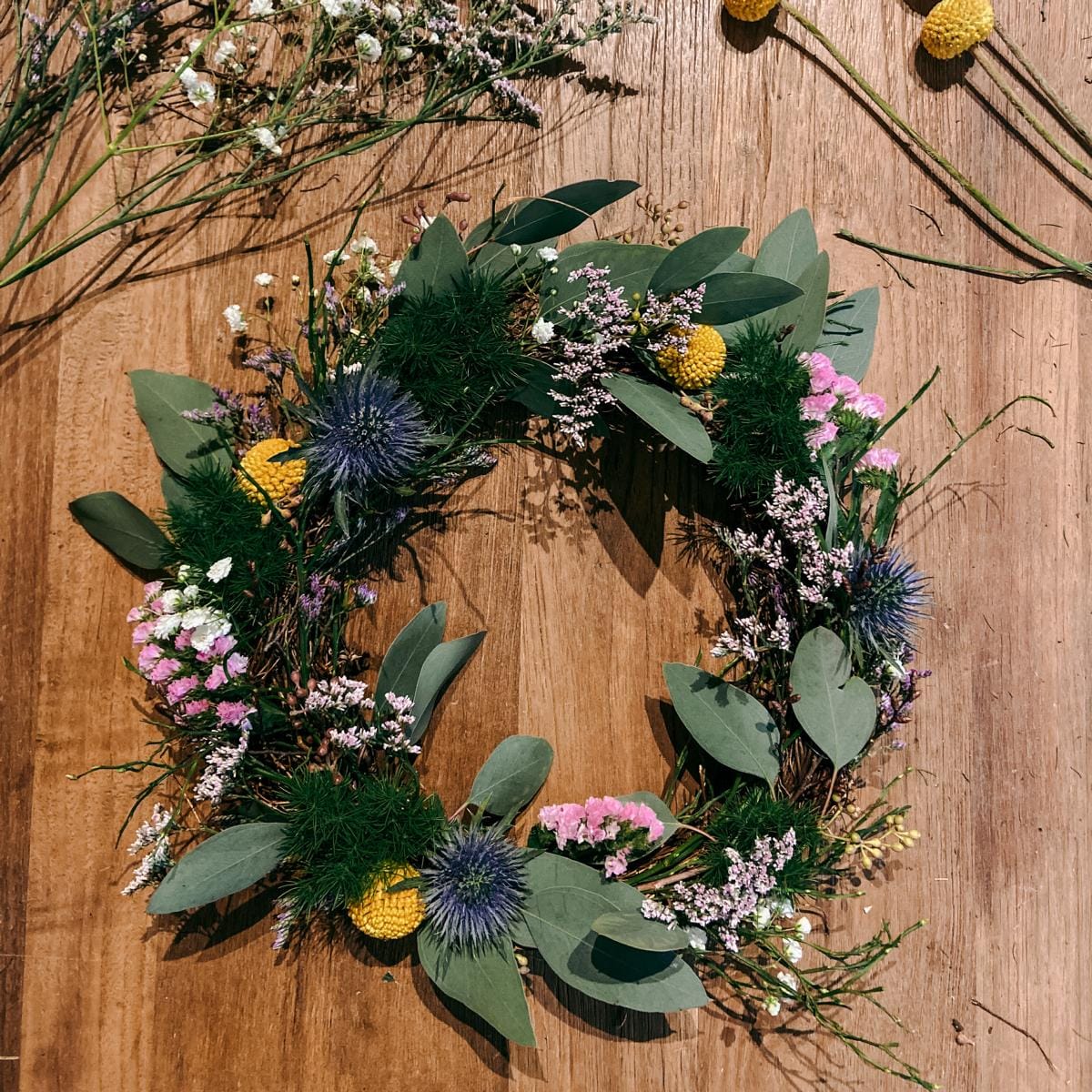 Bunter Frühlingskranz auf Holztisch – DIY Kranzbinden Workshop, ideal als JGA oder Teamevent.