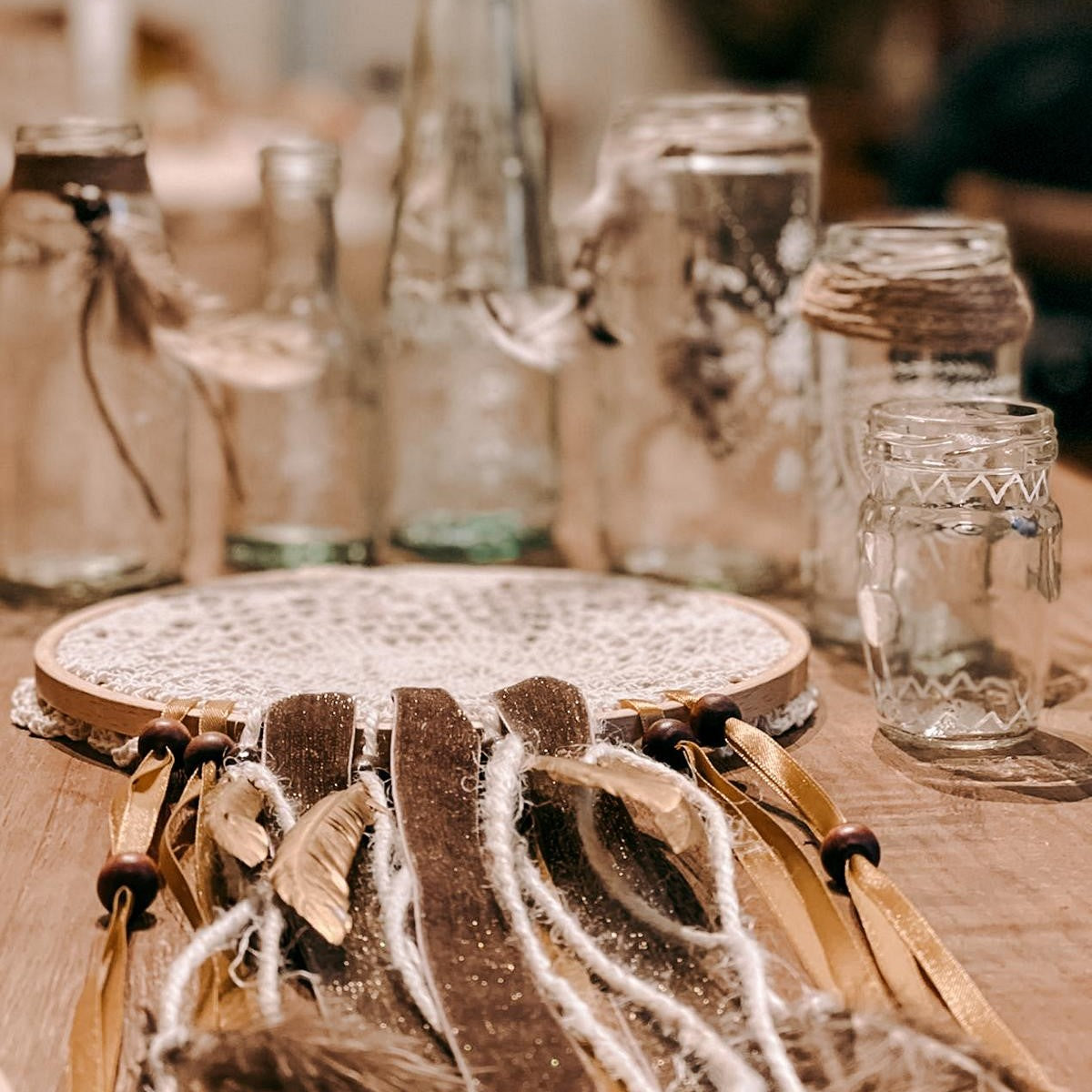 Traumfänger im Boho-Stil, Nahaufnahme mit Gläsern im Hintergrund – Workshop Deko Ideen.