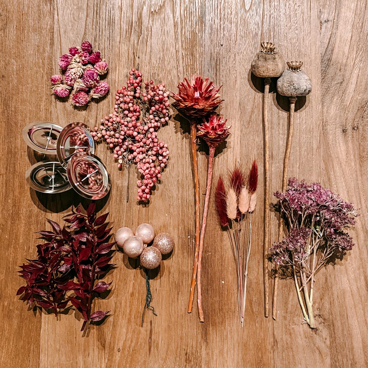 Ordentlich arrangierte rosa Dekorationen auf Tisch – Materialset für Adventskranz DIY Box Rosenrot.