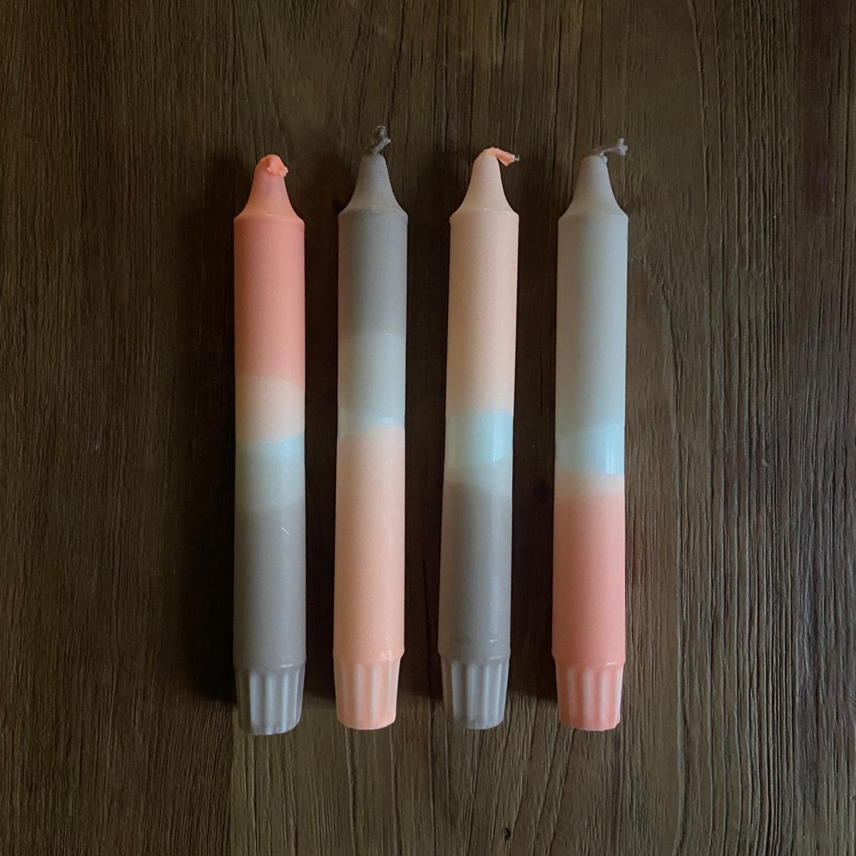 Vier Dip Dye Kerzen „Len“ aus Stearin auf Holztisch neben weißem Kerzenständer – handgetauchte Unikate.