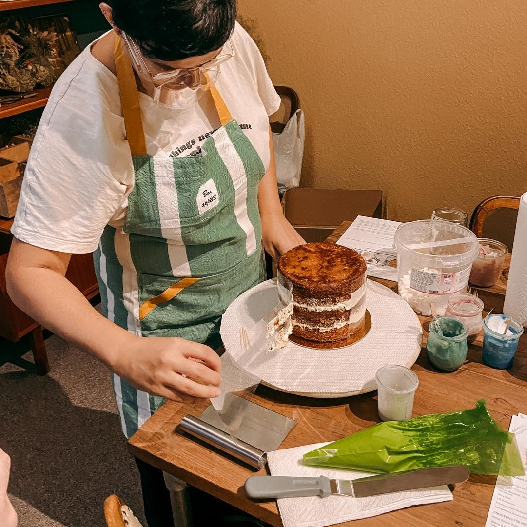 Person bearbeitet Kuchen mit Spatel – Mini Drip Cake Workshop Aktion.