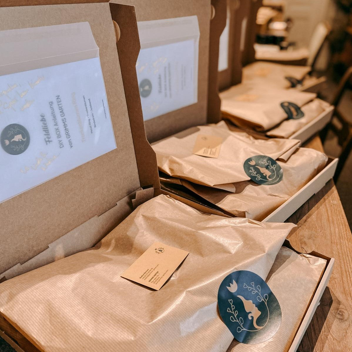 Mehrere DIY Boxen Pfauenauge offen auf Tisch – Trockenblumenringe zum Selbermachen.