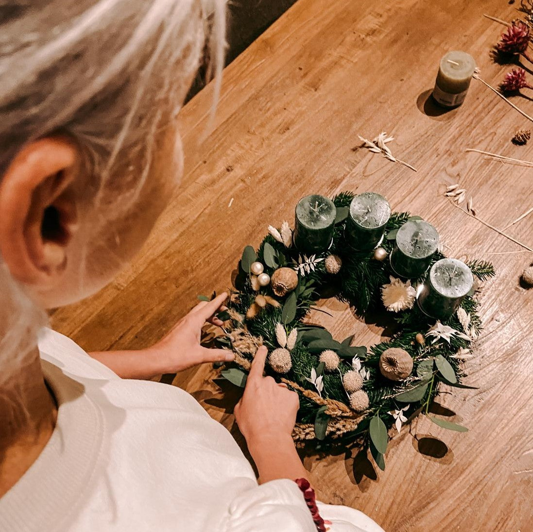 Frau dekoriert Kranz mit Naturmaterialien – nachhaltige Adventsdeko aus DIY Box Hänsel.
