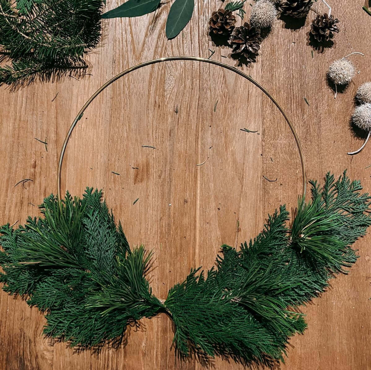 Deko-Ring mit Tannenzweigen liegt auf Tisch – deko ring weihnachten, weihnachtskranz modern.