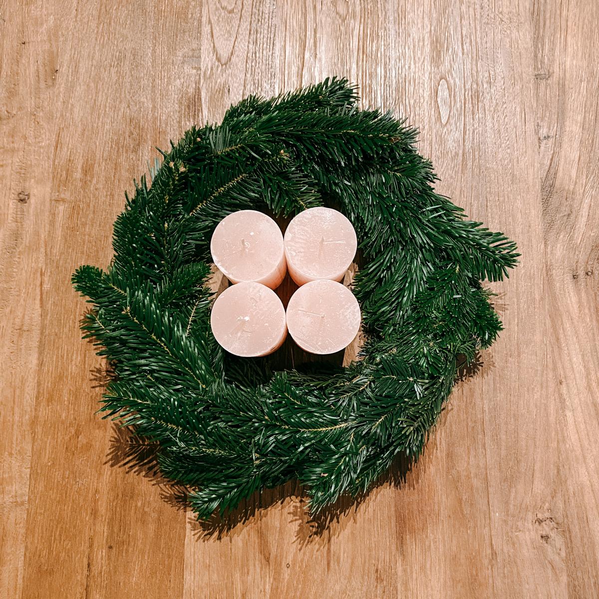 Adventskranz mit vier Kerzen in der Mitte auf Holztisch – stilvolle Weihnachtsdeko Rosenrot.