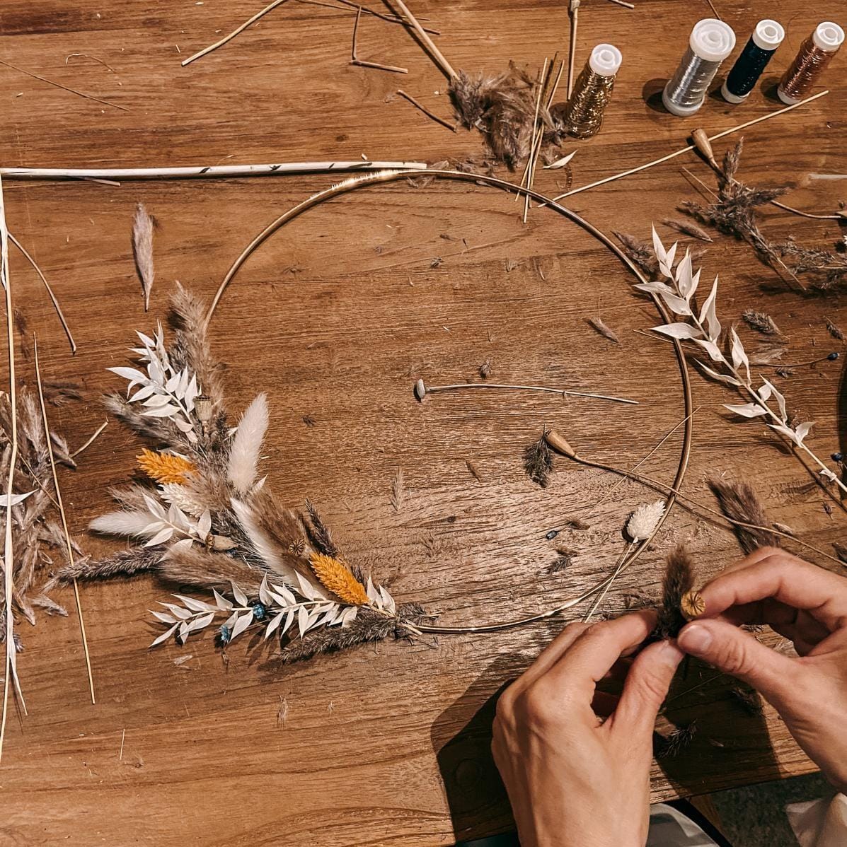 Zwei Hände halten Trockenblume und halbfertigen Ring – Boho-Workshop, DIY, Trockenblumen-Ring.