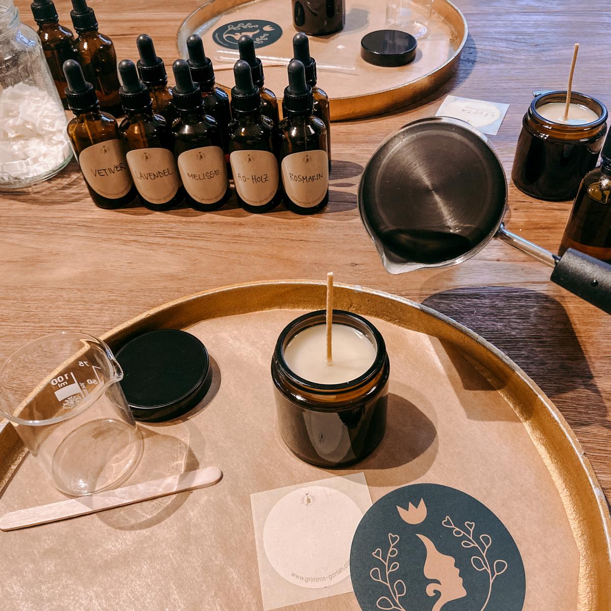 Fertige vegane Kerze im Vordergrund, Duftfläschchen im Hintergrund – Kerzen Workshop für Firmenevents.