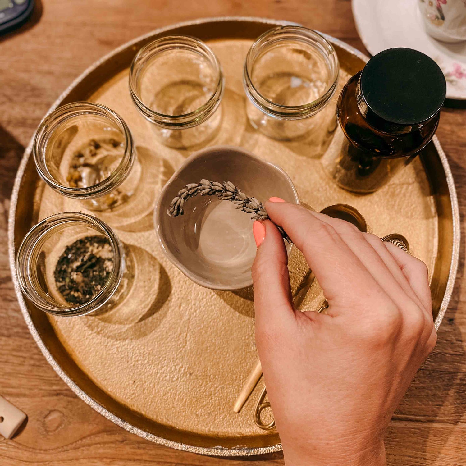 Hand hält Kräuter auf goldenem Tablett mit Gläsern – kräutertee workshop, DIY Tee, Teamevent.