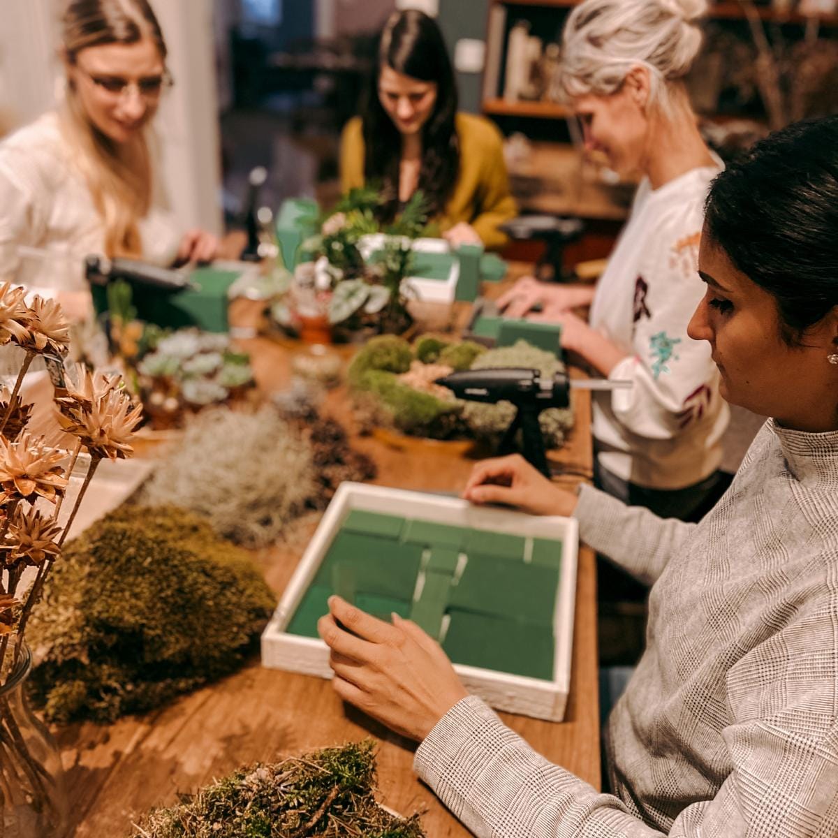 Mehrere Personen arbeiten an ihren Pflanzenbildern – DIY Pflanzenkunst, Workshop Berlin, Teamevent.