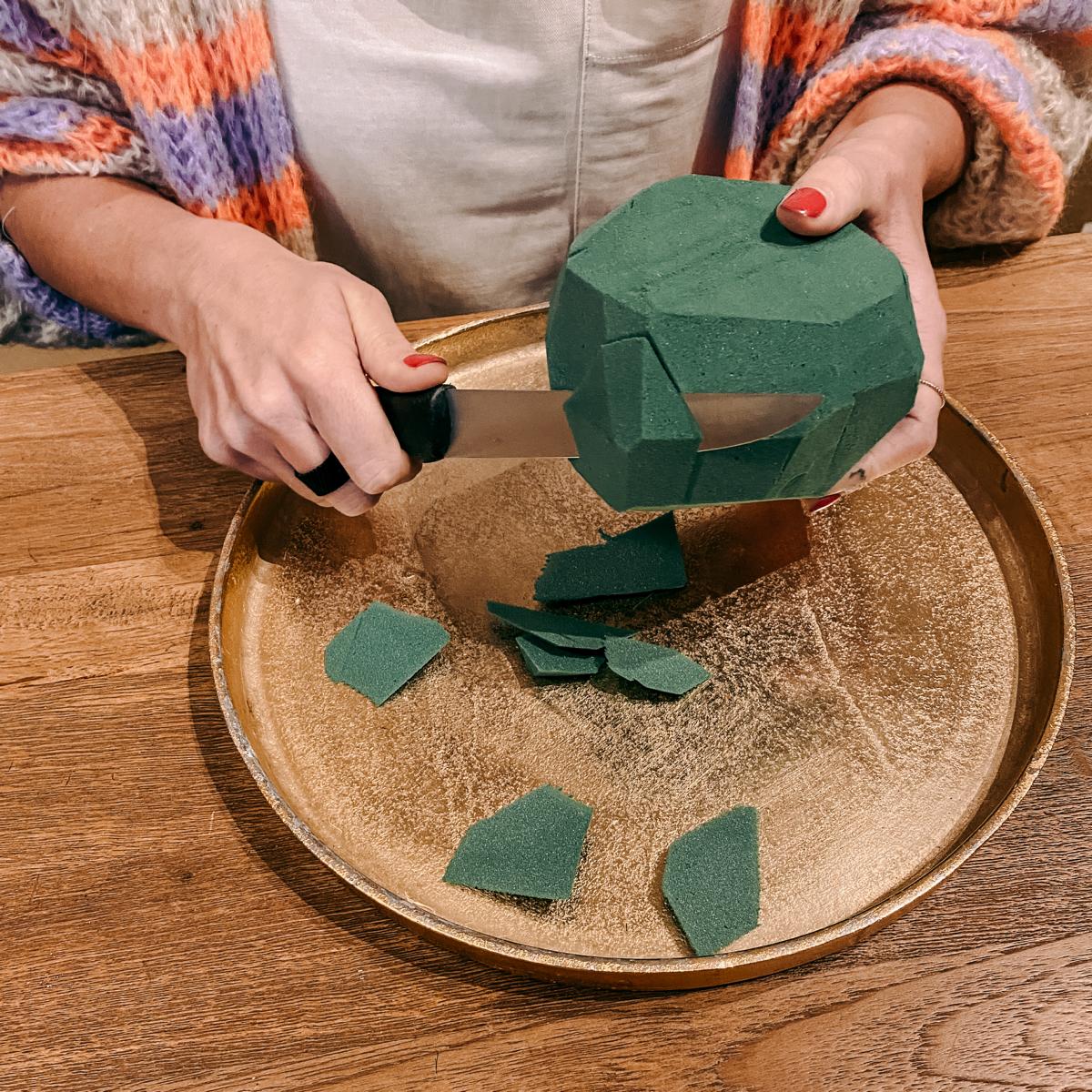 Zwei Hände schneiden Schaumstoff mit Messer – FlowerBall Workshop, Teamevent geeignet.