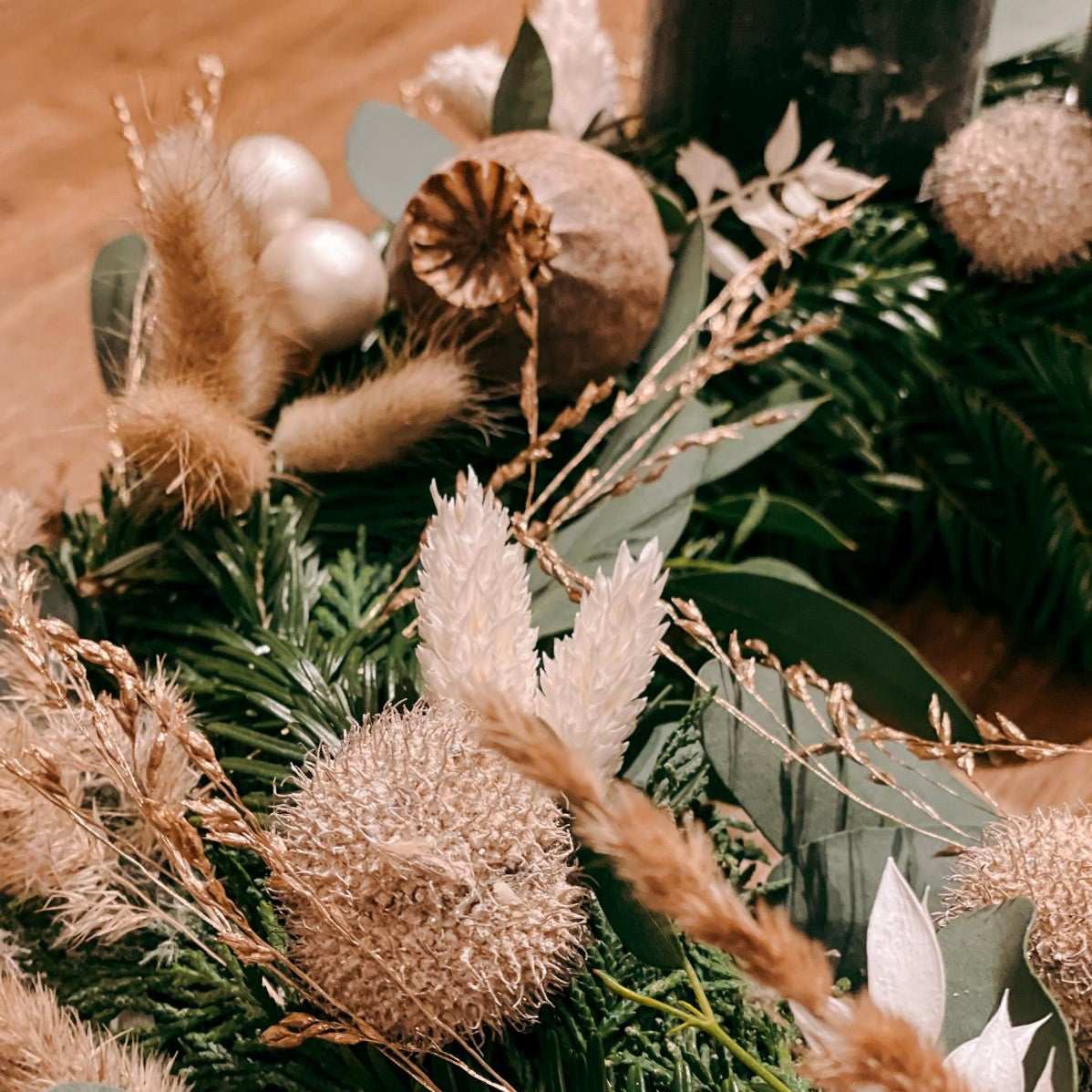 Beige Gräser und weiße Blumen auf grünem Kranz – Adventskranz Hänsel mit Trockenblumen.